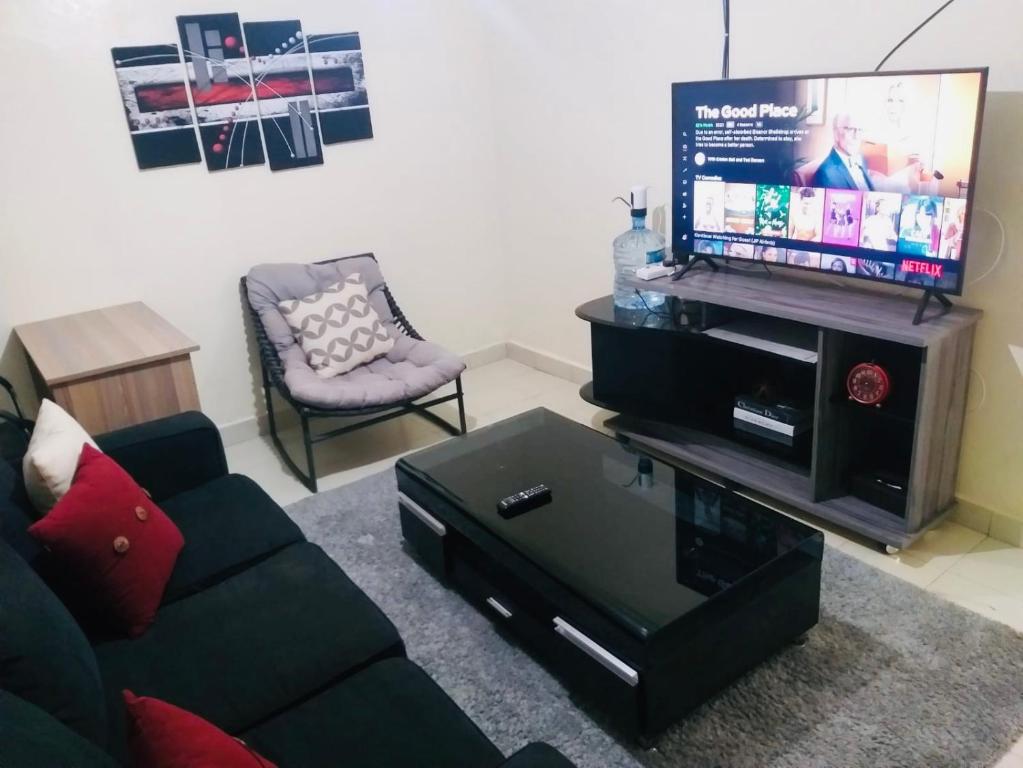 a living room with a couch and a flat screen tv at Joshua’s place: cosy furnished one bedroom apt in Meru
