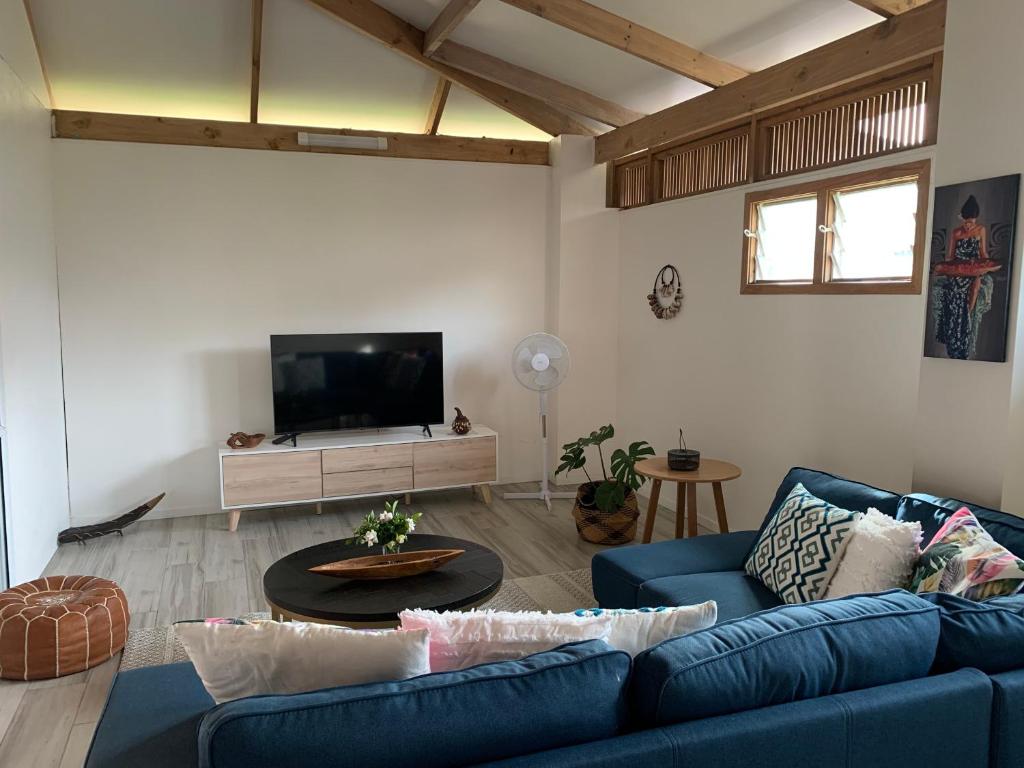 a living room with a blue couch and a tv at Konini Villa in Rarotonga