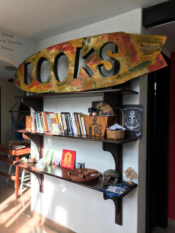 a surfboard hanging on a wall with books at Vibe House Arraial in Arraial do Cabo