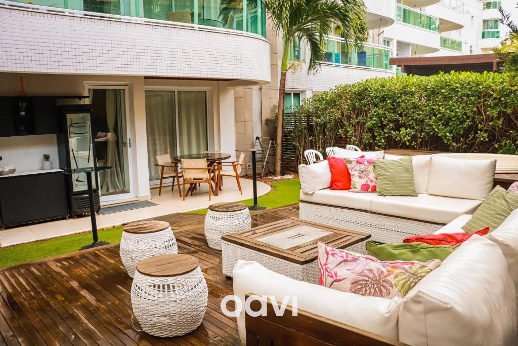 um pátio com sofás brancos, uma mesa e cadeiras em Qavi - Flat com Jacuzzi em Resort Beira Mar Cotovelo #InMare7 em Parnamirim