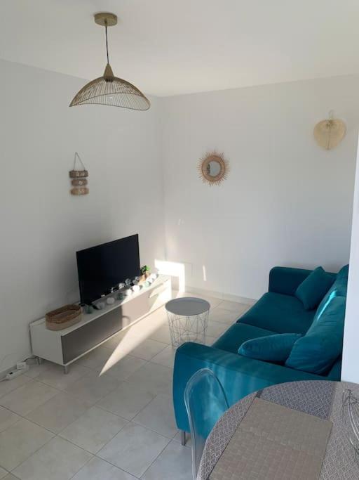 un salon avec un canapé bleu et une télévision dans l'établissement Appartement 35m2 climatisé a 10 min d’Ajaccio, à Alata