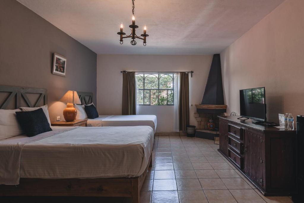 a bedroom with two beds and a television in it at Hotel Casa Santamaría in San Miguel de Allende