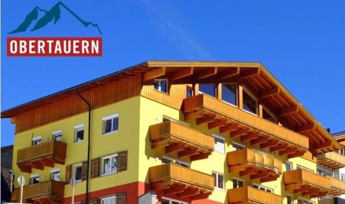 ein gelbes Gebäude mit Balkonen darüber in der Unterkunft alpsrental Apartments Freja Obertauern in Obertauern