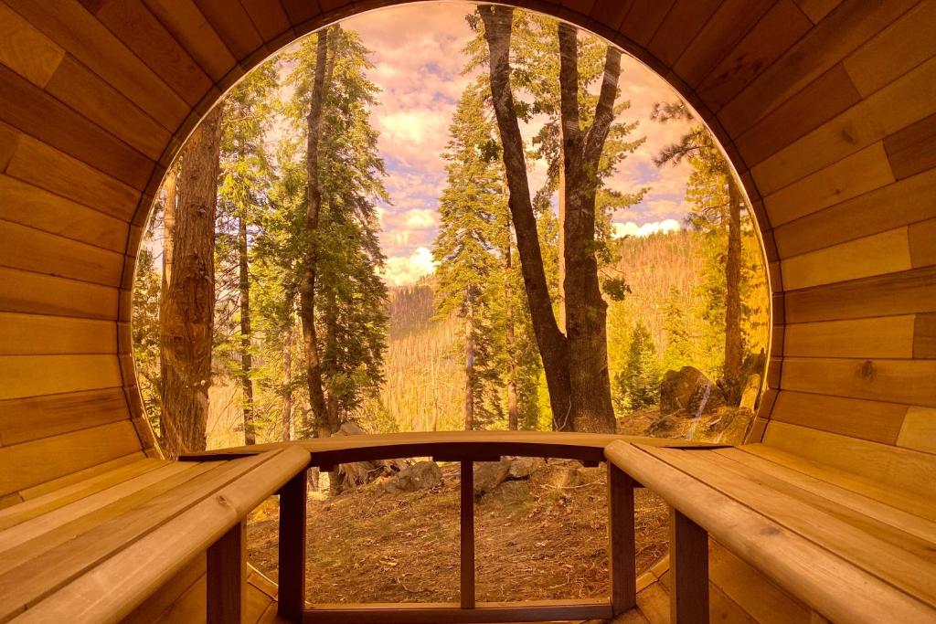 anorthole window in a wooden cabin with a view of a forest at Yosemite West Family Chalet in Yosemite West