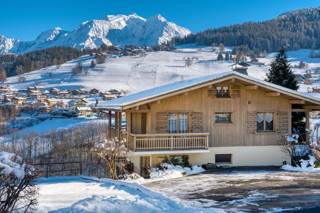 een huis in de sneeuw met bergen op de achtergrond bij Chalet Nessa in Combloux
