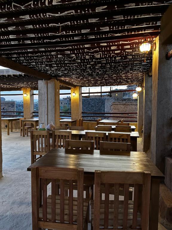 a dining room with wooden tables and chairs at Bait Baityn بيت البيتين in Misfāh