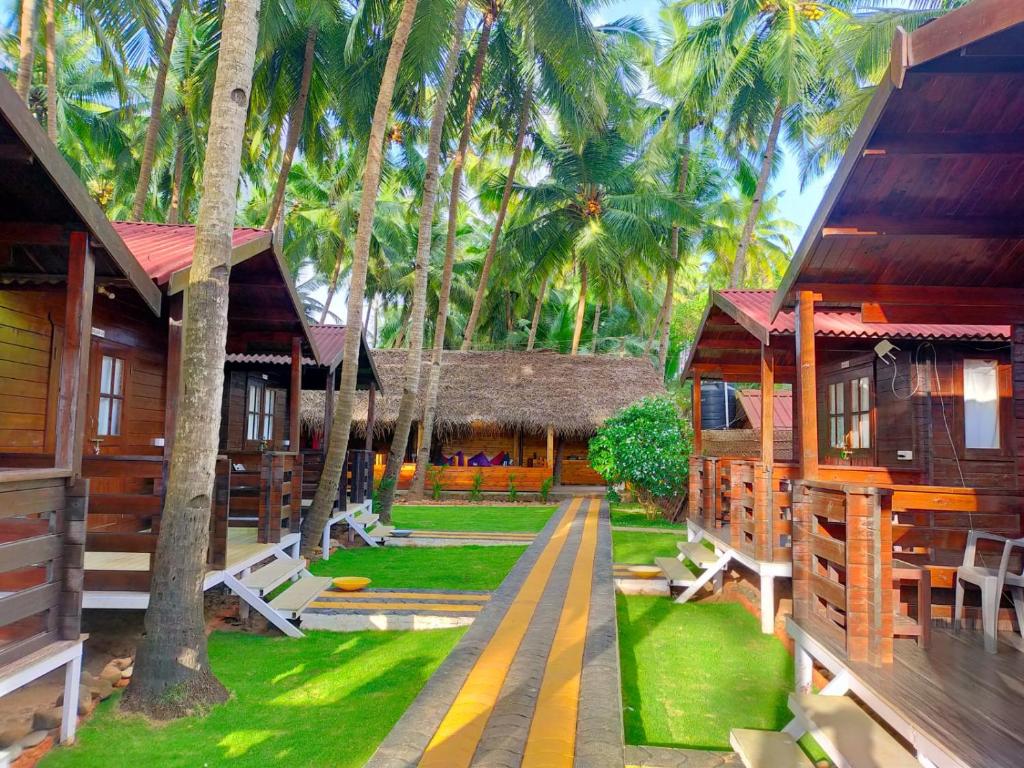 a row of wooden cottages with palm trees at Agonda Paradise in Agonda