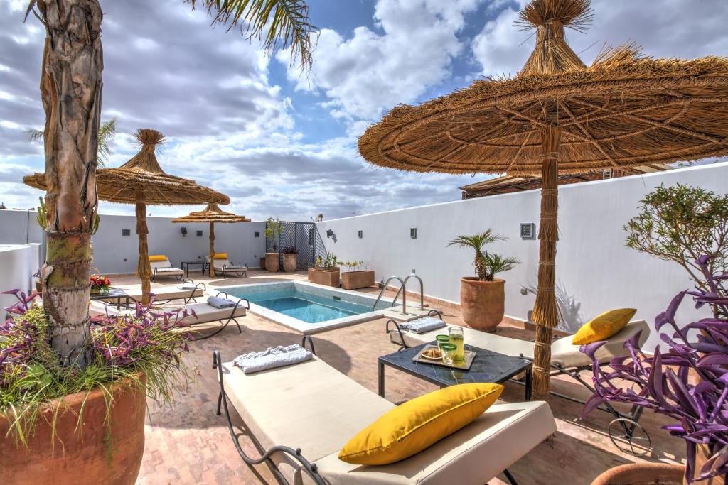 an outdoor patio with a pool and umbrellas at Riad Awa in Marrakesh