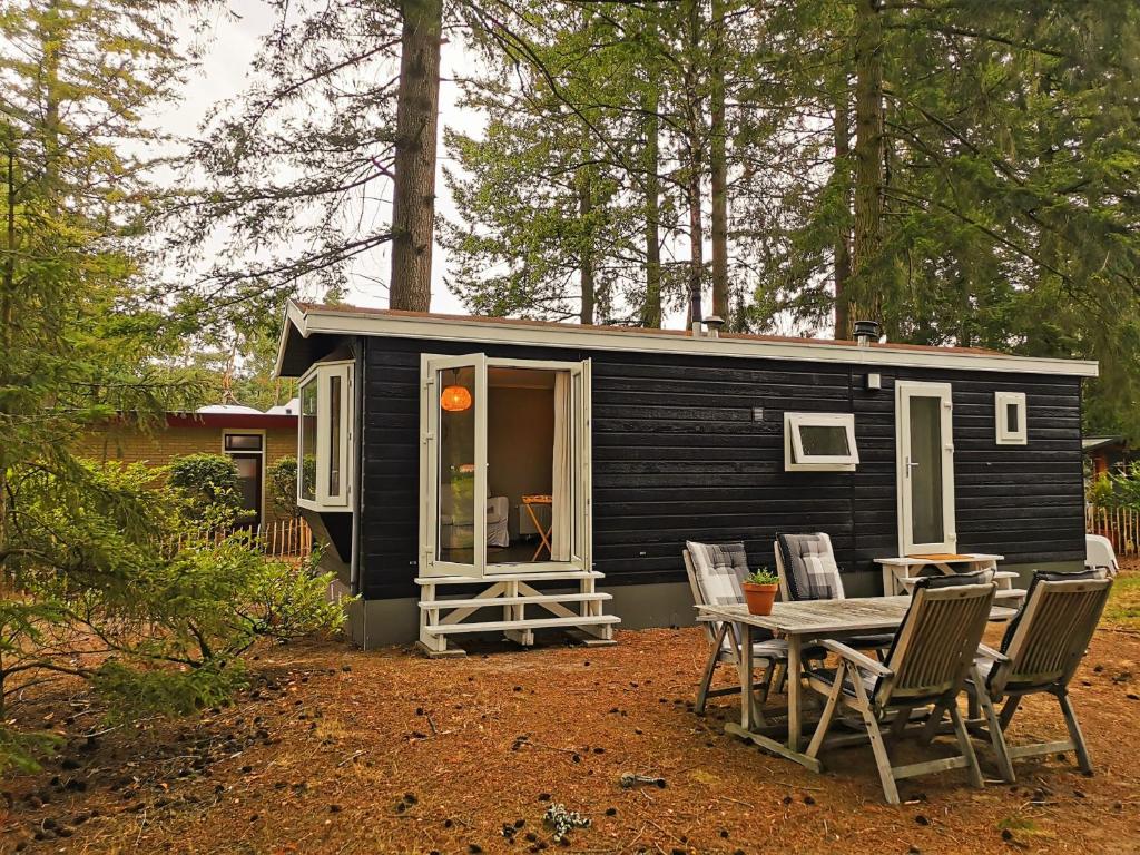 a small black tiny house with a table and chairs at Boslodge 84 in Vorden
