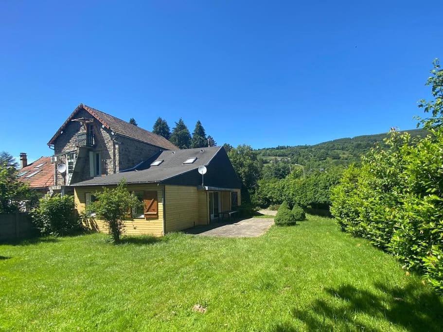 une maison avec une cour avec de l'herbe verte dans l'établissement Maison lumineuse et spacieuse avec terrain, à La Bourboule