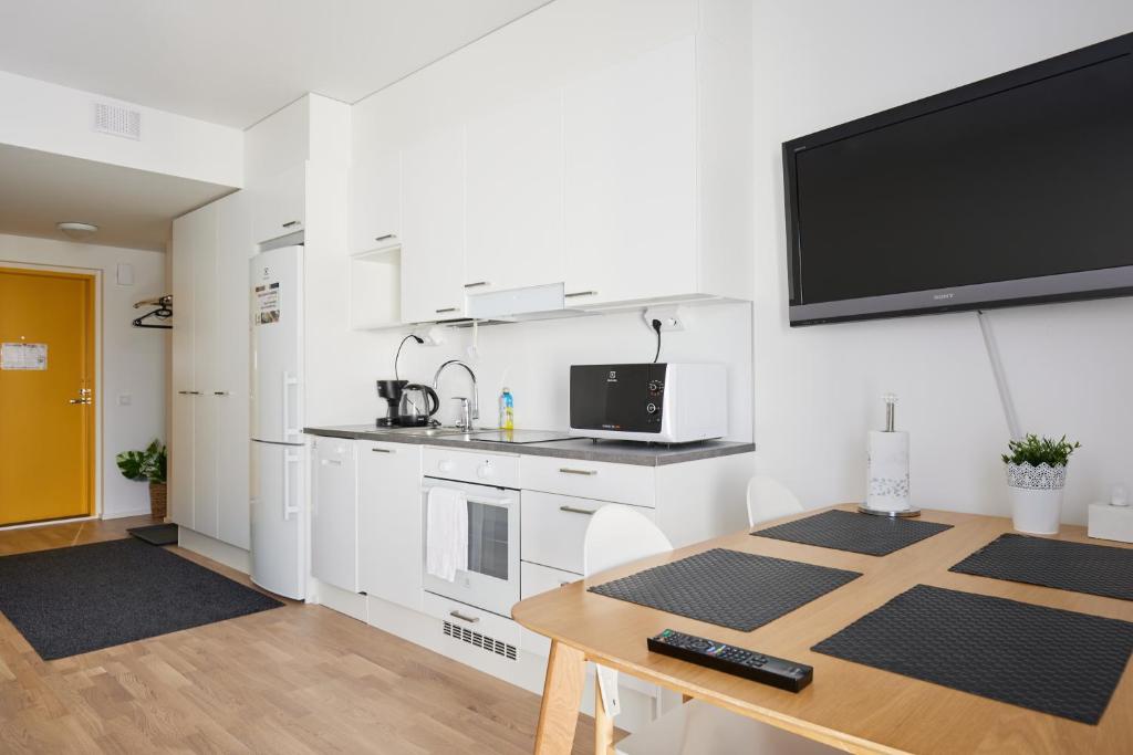 Una cocina con una mesa y un televisor en la pared. en Keskeisen sijainnin uudiskohde, Seamless check-in, Baby crib, en Turku