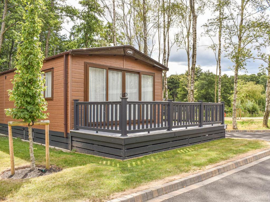 a small cabin with a large deck in a park at Deer Glade Lodge in Landford