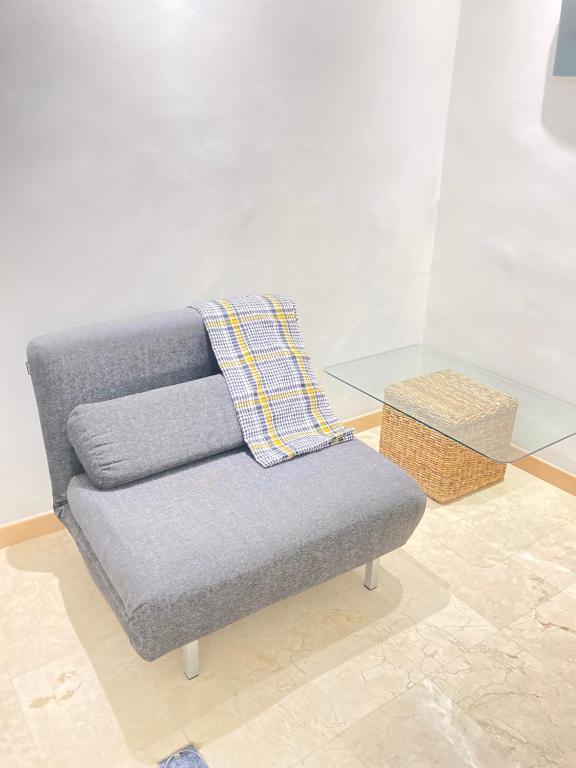 a gray couch with a blanket on it next to a glass table at HATILLO SUITE in Caracas