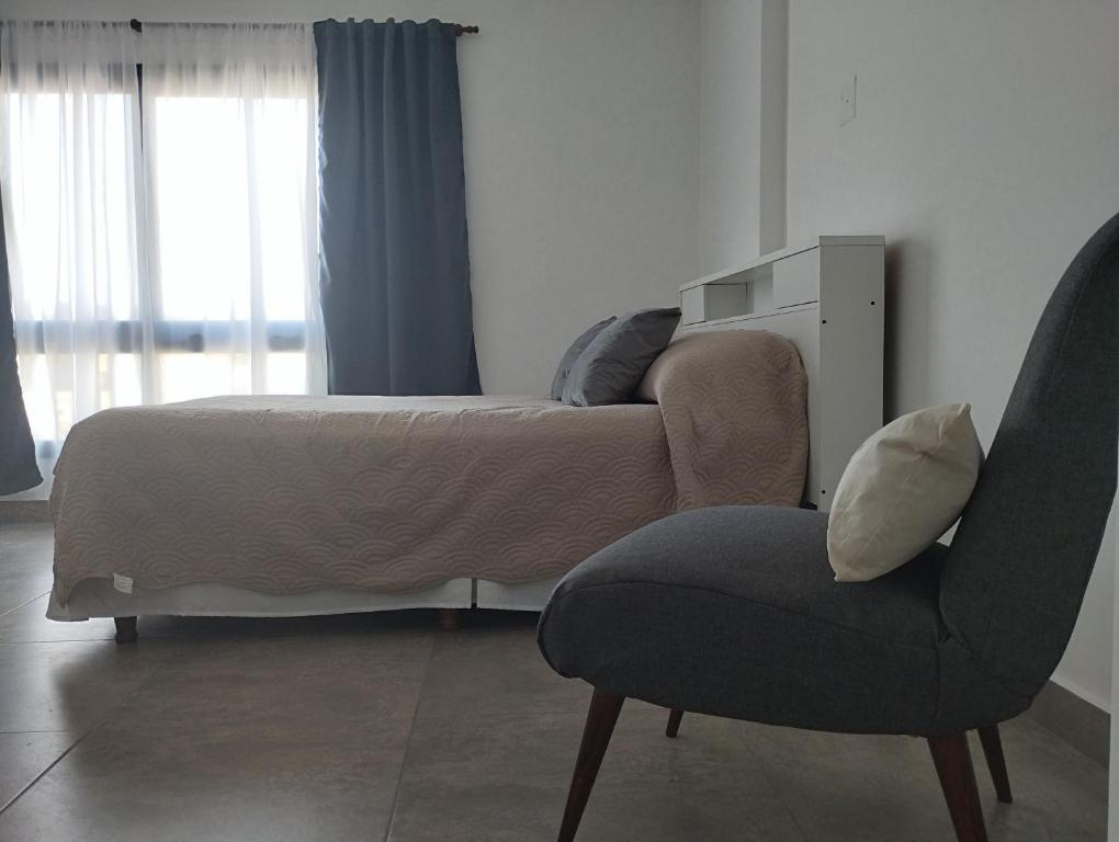 ein Schlafzimmer mit einem Bett und einem Stuhl sowie einem Bett und einem Fenster in der Unterkunft Las Amapolas Jujuy in San Salvador de Jujuy