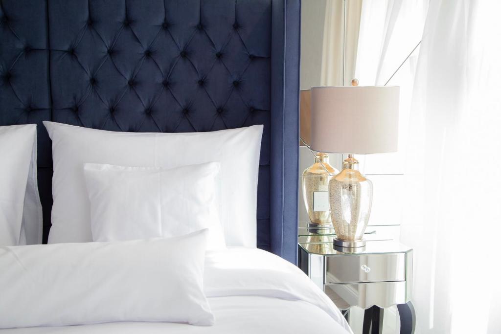 a bedroom with a bed with a blue headboard and a lamp at Ibrahim Boutique Hotel in Kőszeg