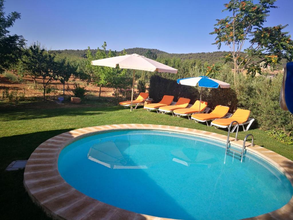 a swimming pool with chairs and an umbrella at Cortijo Los Soledad in El Sauco