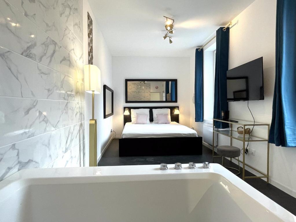 La salle de bains est pourvue d'une baignoire et d'un lit. dans l'établissement Le Vauban, à Mulhouse