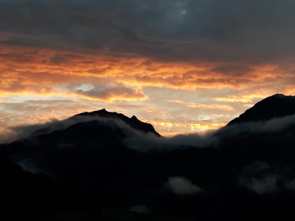 a sunset over a mountain range with clouds at Fernblick Frühstückspension in Schoppernau