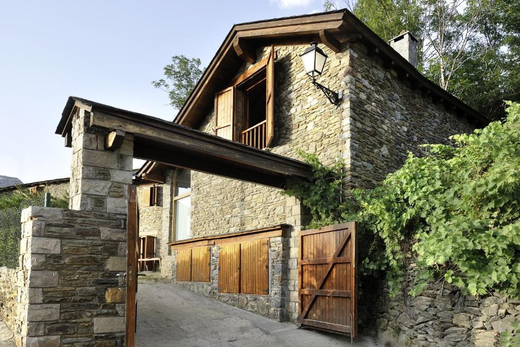 a stone house with wooden doors and a barn at La Caseta de Queixans in Puigcerdà