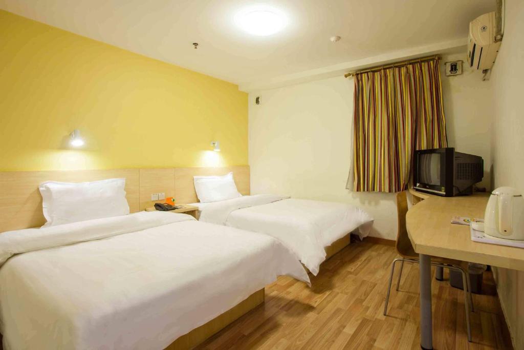 a hotel room with two beds and a television at 7Days Inn Chengdu Huayang Binfen Plaza Branch in Chengdu