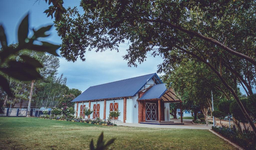 un petit bâtiment blanc avec un toit bleu dans l'établissement Warm Karoo, à Bloemfontein