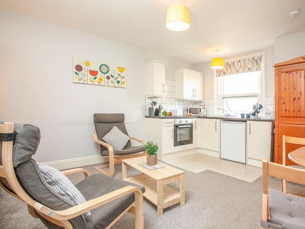a living room with two chairs and a kitchen at Apartment Eleven - Uk39864 in Paignton