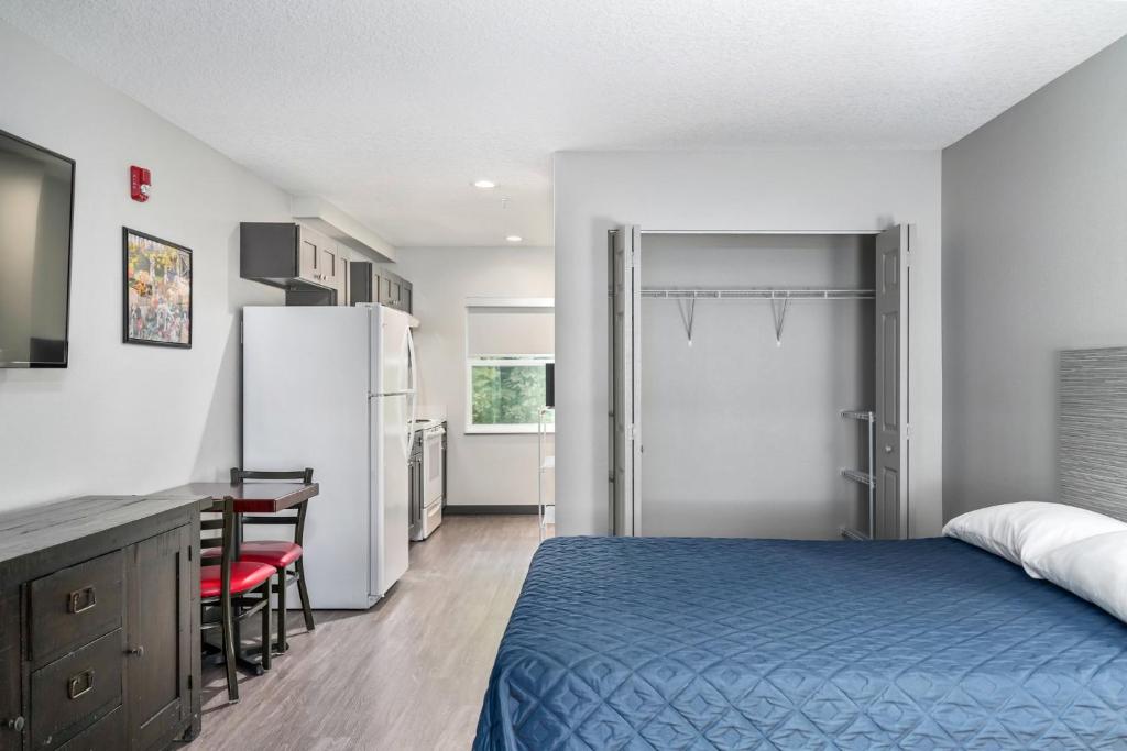 a bedroom with a bed and a desk and a refrigerator at Ocala Suites in Ocala