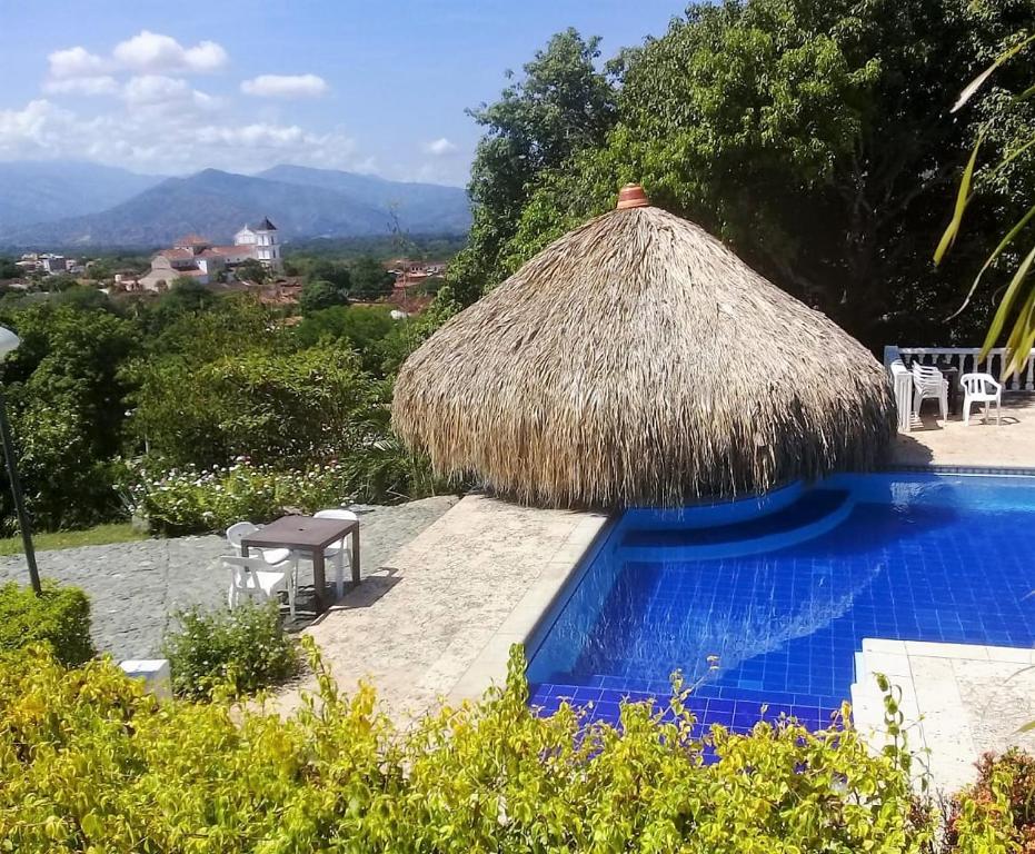 ein Resort mit einer Strohhütte und einem Pool in der Unterkunft Hostal finca Palermo in Santa Fe de Antioquia