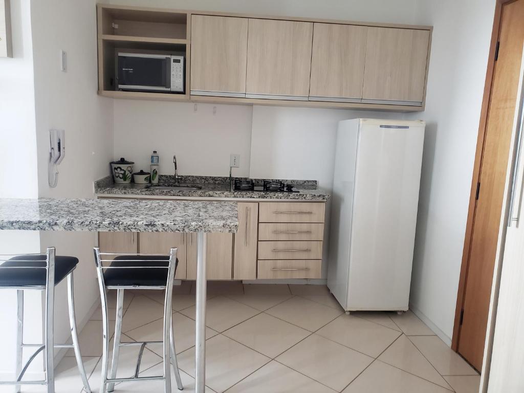 een keuken met een koelkast en een aanrecht met krukken bij Spot Residence São Carlos 700m da USP in São Carlos