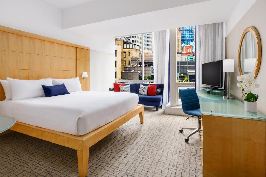 a bedroom with a bed and a desk and a tv at Millennium Premier New York Times Square in New York