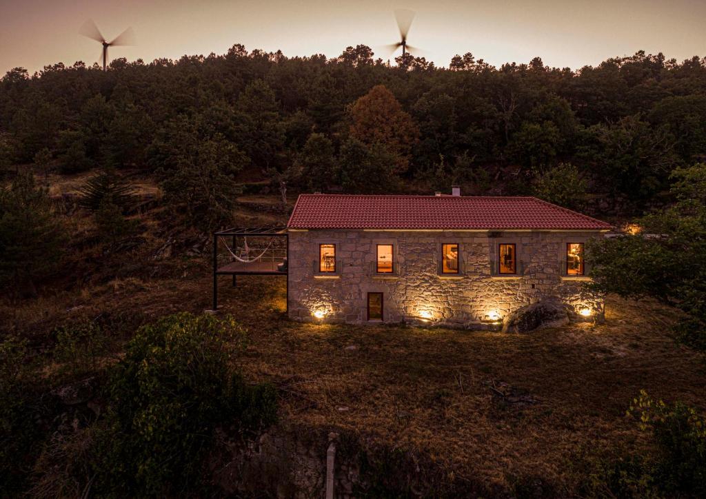 a stone house with lights in a field at night at Casa da Moiroa in Sendim