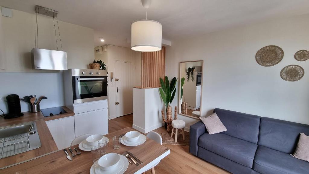 a living room with a blue couch and a kitchen at Cristal 2 in Issoire