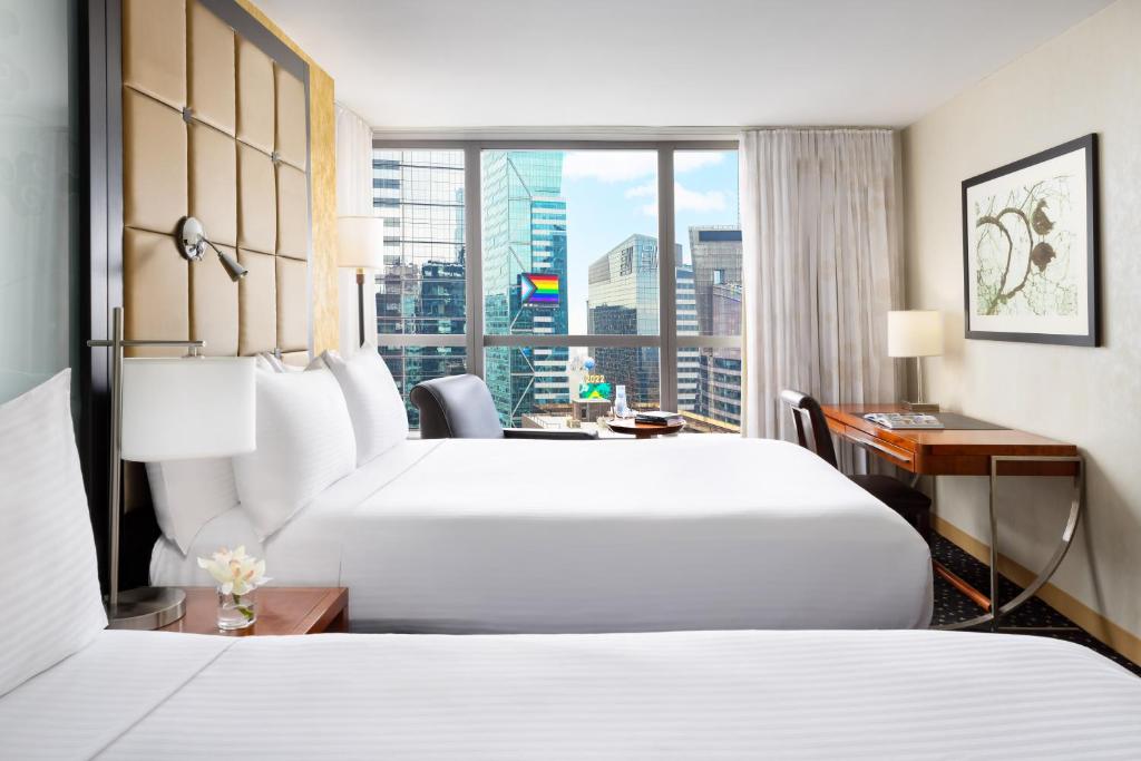 a hotel room with two beds and a desk and a window at Millennium Hotel Broadway Times Square in New York