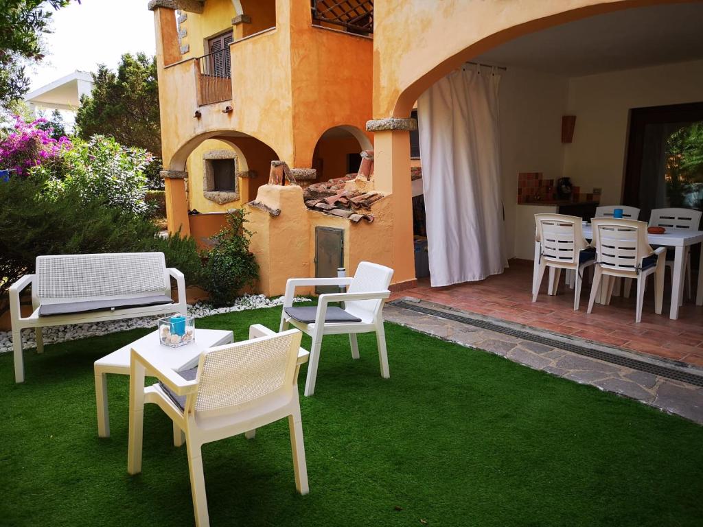 een patio met witte stoelen en tafels op het gras bij Insardinia House trilocale a 200mt dalla spiaggia in Olbia