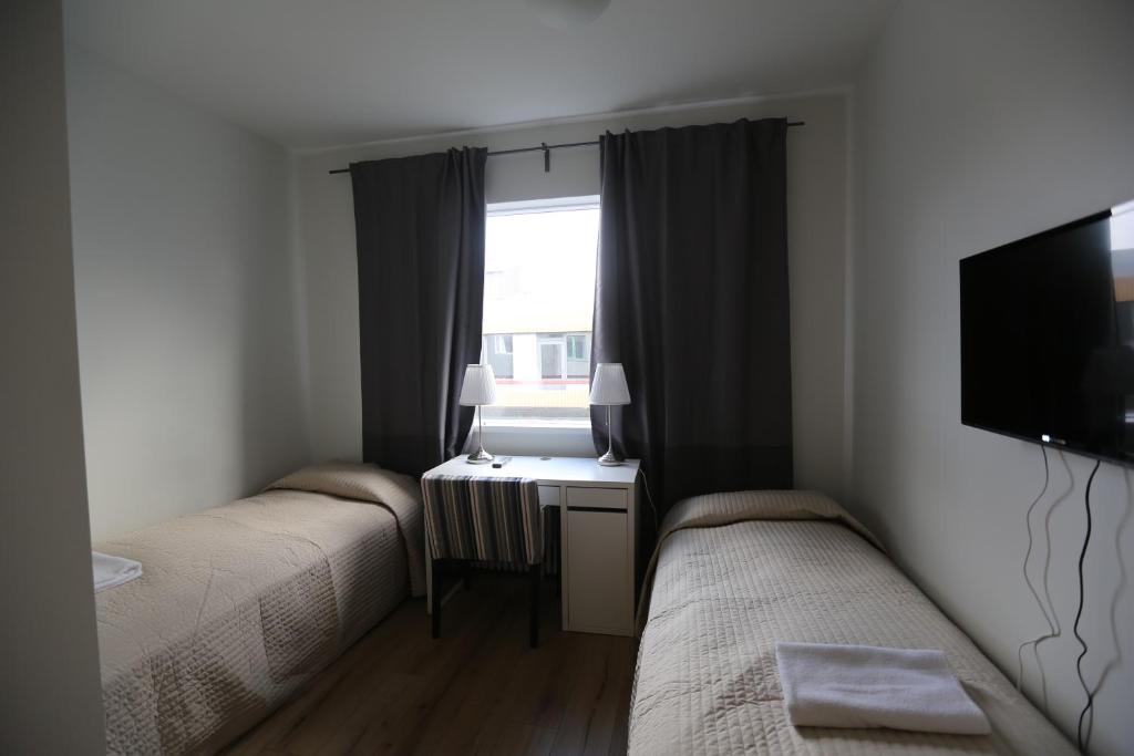 a room with two beds and a desk and a window at 100 Iceland Hotel in Reykjavík