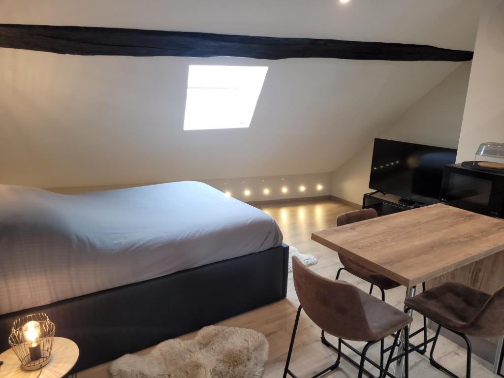 a bedroom with a bed and a table and a television at Studio au centre-ville in Saint-Jean-de-Losne