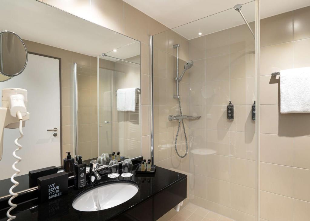 La salle de bains est pourvue d'un lavabo et d'une douche. dans l'établissement The Rilano Hotel Hamburg, à Hambourg