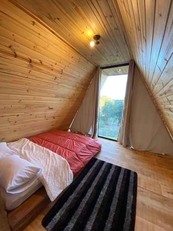 um quarto com uma cama num quarto com uma janela em Chalés entre Nuvens em Campos do Jordão