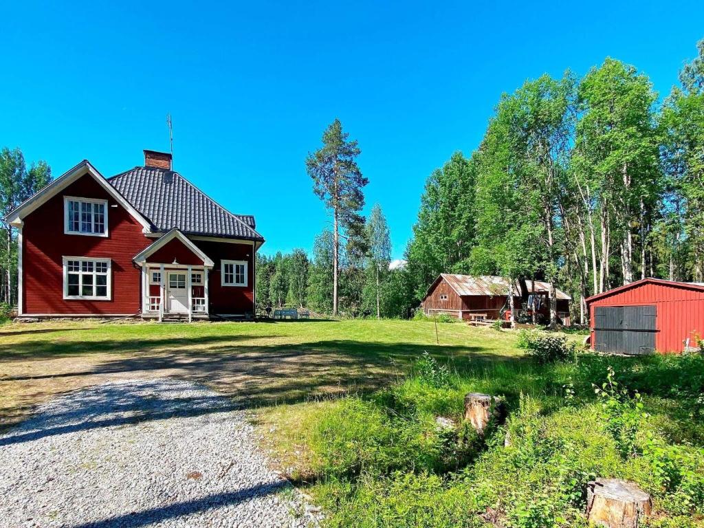 a red house and a red barn on a field at Holiday home LYCKSELE in Lycksele