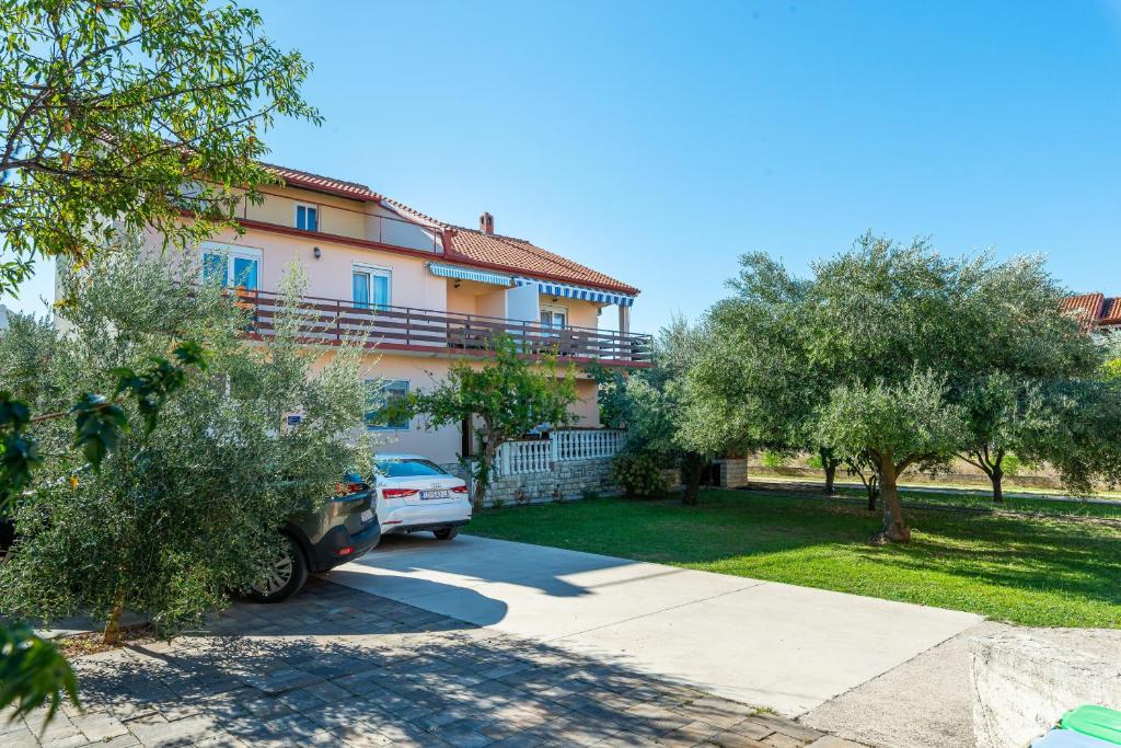 una casa con un coche aparcado en la entrada en Apartments by the sea Bibinje, Zadar - 5786, en Bibinje