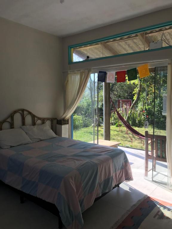 a bedroom with a bed and a large window at Paikea Hostel Praia do Rosa in Praia do Rosa