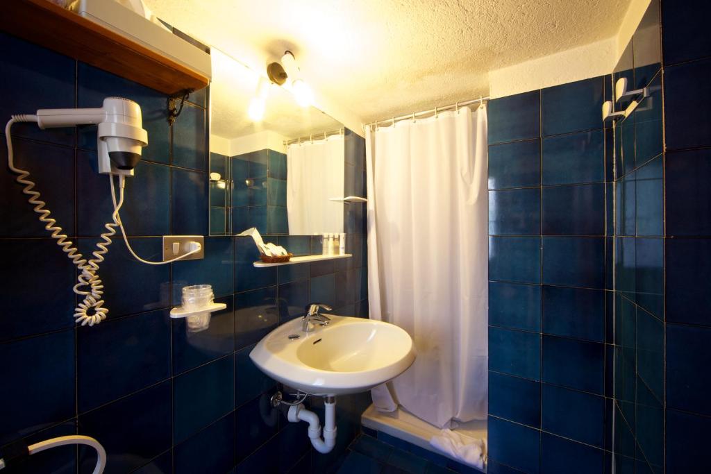 a blue tiled bathroom with a sink and a shower at Hotel Dolonne in Courmayeur