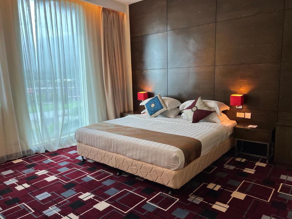 a bedroom with a large bed and a large window at SSL Traders Hotel in Taiping