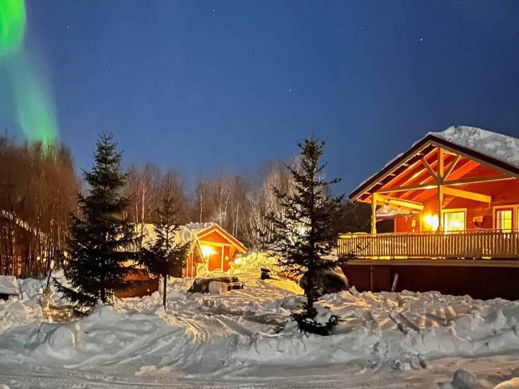 a log cabin in the snow at night with the northern lights at 7 person holiday home in JARFJORD in Karpbukt