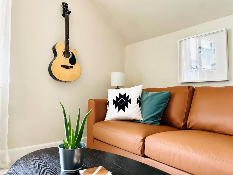 Sala de estar con sofá y guitarra en la pared en Immaculate, Newly Renovated 1 Bedroom Apt Near NYC, en Hawthorne