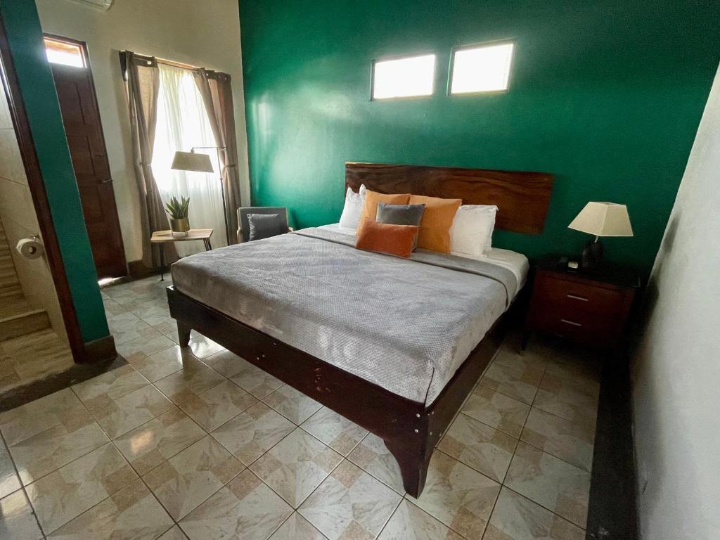 a bedroom with a bed with a green wall at Hotel Wilson Condega in Liberia
