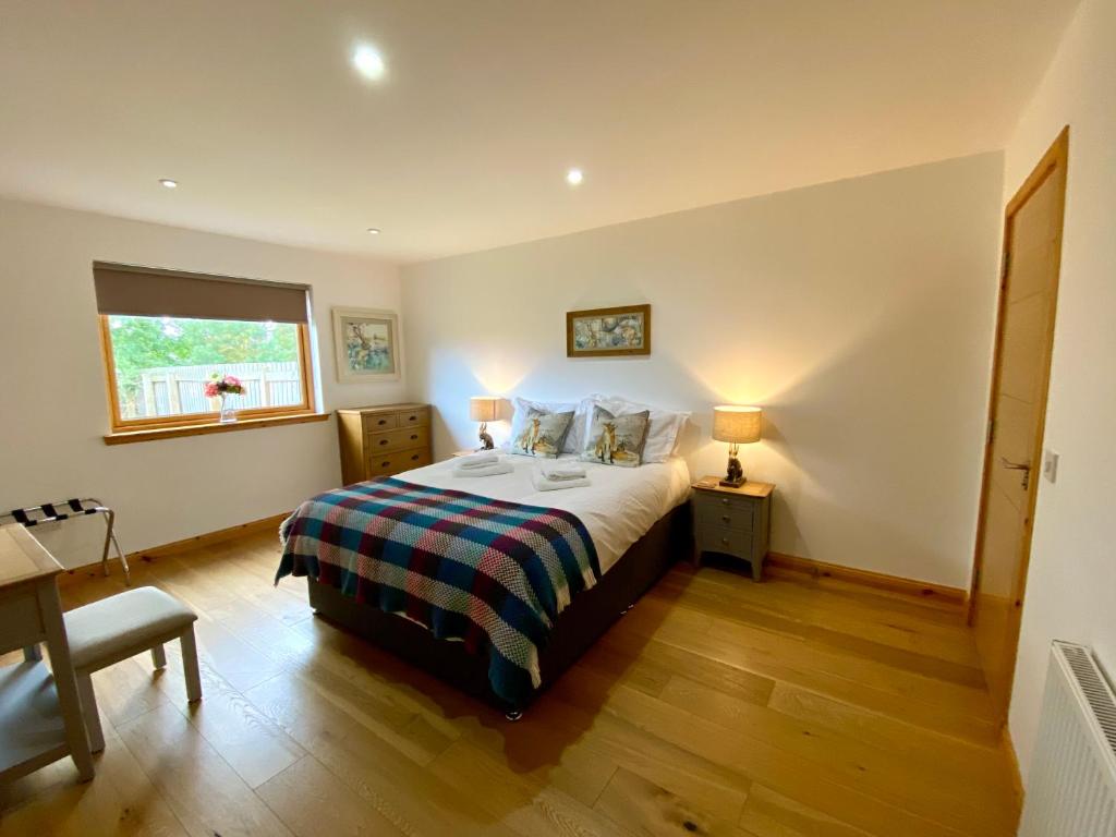 een slaapkamer met een bed, een bureau en een raam bij Teaghlach, Cairngorms - Escape Cottages Scotland in Newtonmore
