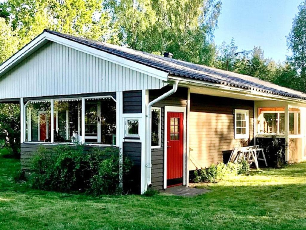 een klein huis met een rode deur in een tuin bij 8 person holiday home in BERGKVARA in Bergkvara
