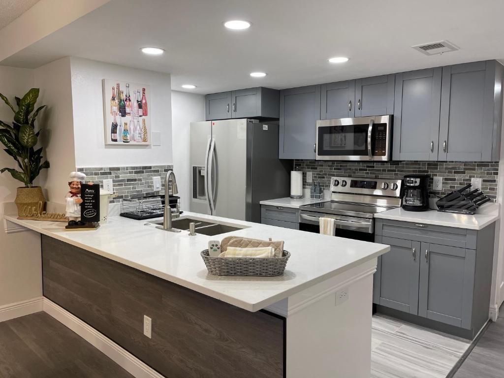 Una cocina con gabinetes grises y una encimera blanca. en Fabulous Apartment 8 pax close Disney, en Kissimmee