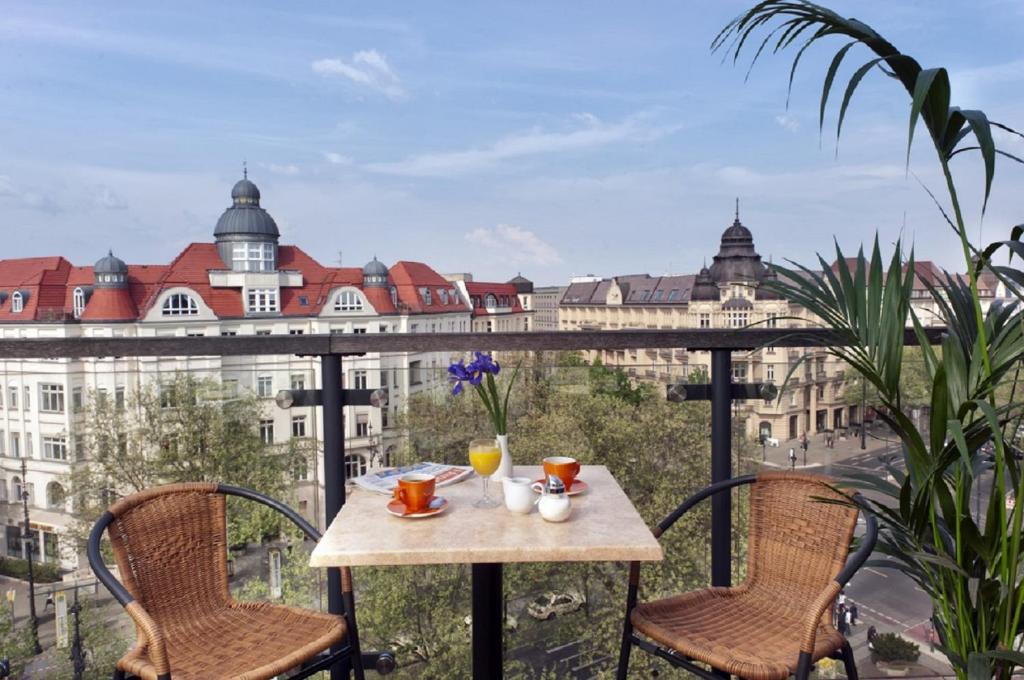 a table and chairs on a balcony with a view of a city at Come Inn Berlin Kurfürstendamm in Berlin